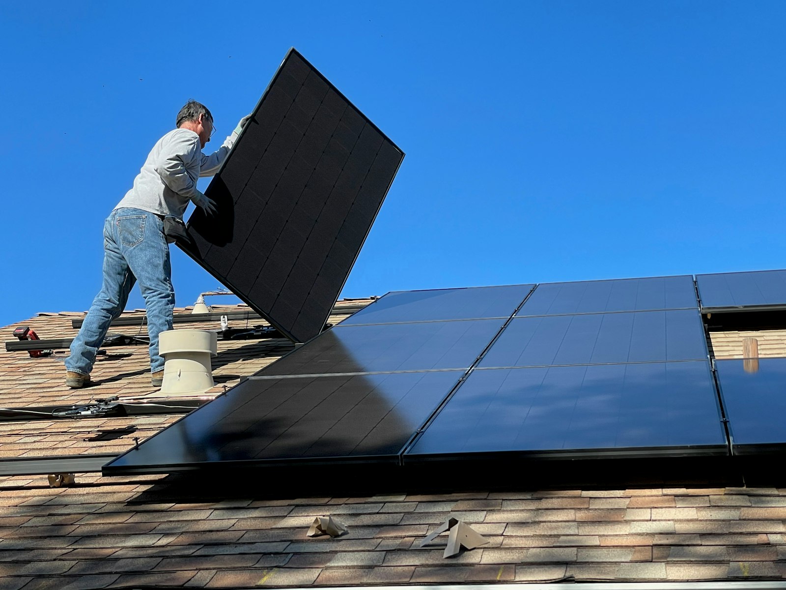 Montér usazuje fotovoltaický panel na střechu